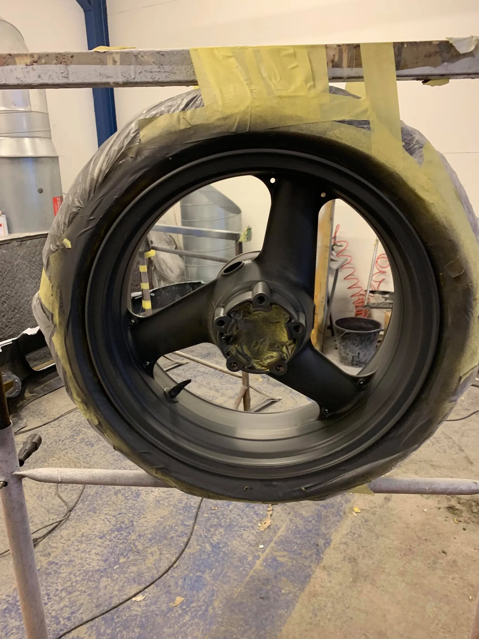 A black wheel painted and drying in the workshop