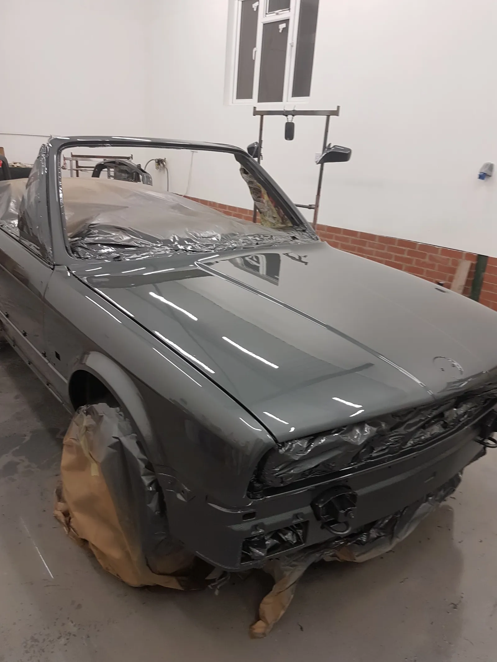 An older car taken back to grey primer all over during a restoration in the workshop